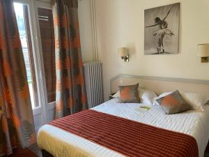 a bedroom with a bed with an orange blanket and a window at Hôtel-Restaurant "Les Rochers" in La Balme-de-Sillingy