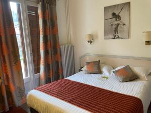 - une chambre avec un lit doté d'une couverture orange et d'une fenêtre dans l'établissement Hôtel-Restaurant "Les Rochers", à La Balme-de-Sillingy