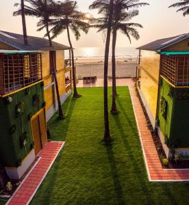 a lawn with palm trees in front of the beach at The O2H Agonda Beach Resort in Agonda