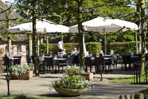 een restaurant met tafels, stoelen en parasols bij Landhotel Diever in Diever