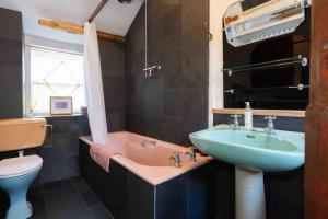 a bathroom with a sink and a tub and a toilet at Janies Cottage~ Mousehole~Eclectic Interiors & Vintage Charm in Mousehole