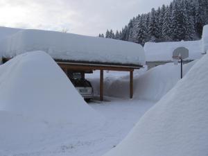 un garaje cubierto de nieve con un coche aparcado debajo en Apartment Jakelj, en Kranjska Gora
