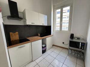 a small kitchen with white cabinets and a window at Appartement cosy - 3e arr in Marseille
