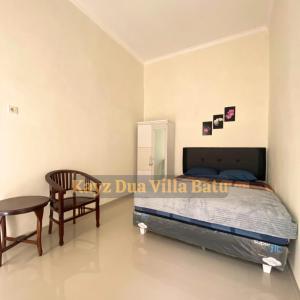 a bedroom with a bed and a table and a chair at Kayz Dua Villa Batu Dengan Kolam Renang Pribadi in Tlekung