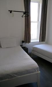 Duporth Guest House في بينزانس: غرفة نوم بسريرين ونافذة