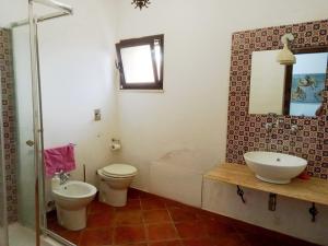 ein Badezimmer mit einem Waschbecken, einem WC und einem Spiegel in der Unterkunft Villa Maruzza (Sicilia Bedda) in Carini