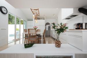 uma cozinha com armários brancos e uma mesa com cadeiras em Selecta Casa Orquídea em Casares