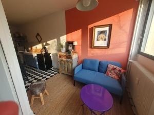een woonkamer met een blauwe bank en een keuken bij L'atelier cosy in Beaune