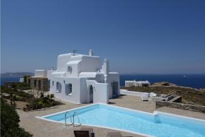 ein großes weißes Gebäude mit einem Pool davor in der Unterkunft Awesome Mykonos Villa - 5 Bedrooms - Villa Houlston - Great Panoramic Sea Views in Fanari