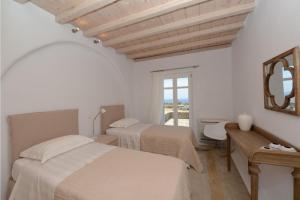 a bedroom with two beds and a desk and a mirror at Awesome Mykonos Villa - 5 Bedrooms - Villa Houlston - Great Panoramic Sea Views in Fanari