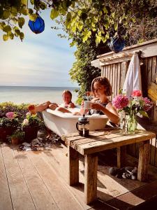 a man and a woman sitting in a bath tub on the beach at The Lighthouse Cabin in Borre