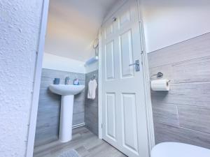 a bathroom with a sink and a white door at Snug, Dog Friendly, Country Cottage in Worle +10 photos