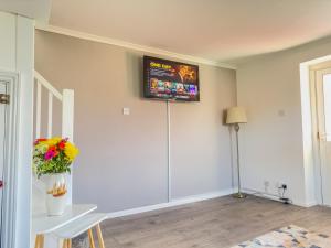 a living room with a television on the wall at Snug, Dog Friendly, Country Cottage in Worle