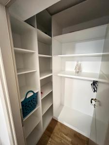 a walk in closet with white shelves and a blue basket at 2 rooms apartment Airy & Bright Chic in Iaşi