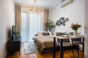 a bedroom with a bed and a table and a couch at Vivando - Bright 1BR - Green View Balcony - Parking in Bucharest