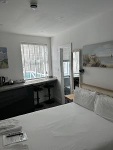 a bedroom with a bed and a desk and windows at Duporth Guest House in Penzance