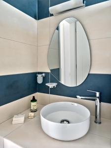 La salle de bains est pourvue d'un lavabo blanc et d'un miroir. dans l'établissement Villa Maria - Naoussa Fishes Blue & Grey Suite, à Náoussa