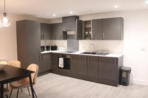 a kitchen with grey cabinets and a table and chairs at The Nest at Hemel Hempstead in Hemel Hempstead