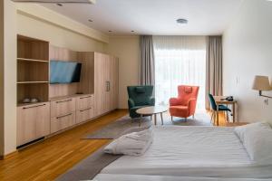 a hotel room with a bed and a tv and chairs at Royal SPA Residence in Birštonas