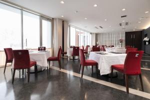 une salle à manger avec des tables blanches et des chaises rouges dans l'établissement HOKURYUKO HOTEL North NAGANO, à Iiyama