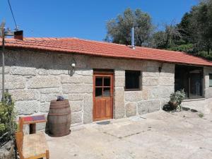 una pequeña casa de piedra con una puerta de madera y un barril en Country House - Hippie Garden, en Vieira do Minho