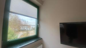 a window with a green frame and a flat screen tv at Pokoje na Cyplu in Mrągowo