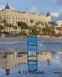 uma cadeira azul sentada na praia em frente a um edifício em Bel appartement proche de cannes em Vallauris
