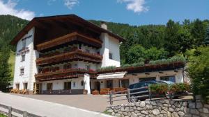 un edificio con un'auto parcheggiata di fronte di Albergo Alisander a Corvara in Badia