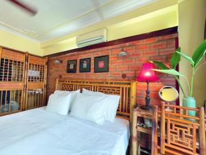 - une chambre avec un lit blanc et un mur en briques rouges dans l'établissement May - Maison De Charme 02, à Hanoï