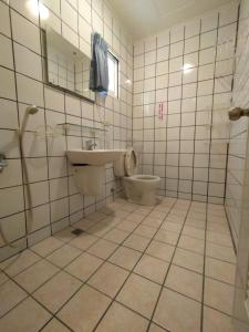 a tiled bathroom with a toilet and a sink at Penghu Le You You Homestay in Magong