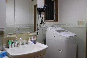 La salle de bains est pourvue d'un lavabo et d'un lave-linge. dans l'établissement Niji Homestay, à Osaka