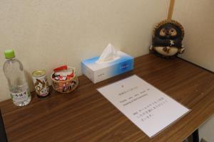 a desk with a box of tissues and a bottle of water at Niji Homestay in Osaka