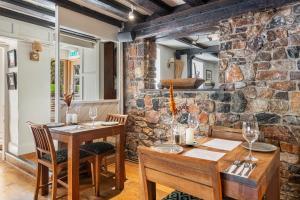 una sala da pranzo con tavoli e sedie in legno e un muro di pietra di The Bickley Mill a Newton Abbot
