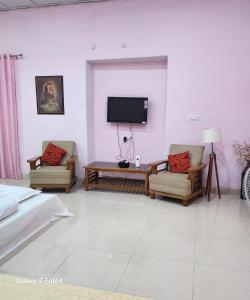 uma sala de estar com 2 cadeiras e uma televisão de ecrã plano em NICTBS em Prayagraj