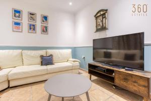 ein Wohnzimmer mit einem Sofa und einem großen TV in der Unterkunft Charming & Cosy 2BR home with WIFI in Birgu by 360 Estates in Vittoriosa