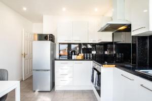 a kitchen with white cabinets and a refrigerator at A cosy 2 bed flat in Swindon in Swindon