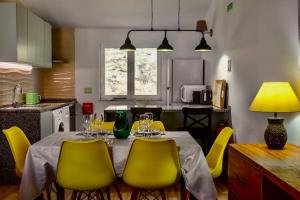 a kitchen with a dining table with yellow chairs at Casas de Santa Maria in Sintra