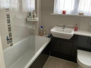a bathroom with a white tub and a sink at Private room in bright detached house in Salisbury