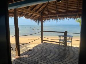 a table and chair on a porch with the beach at Sunset Beach Bungalow Koh Pu in Ko Jum