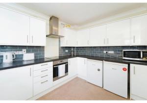 uma cozinha com armários brancos e bancadas pretas em Charming Uxbridge 3BR Home with Parking em Uxbridge