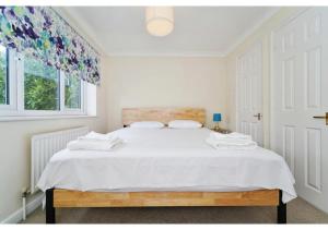 um quarto branco com uma cama grande e lençóis brancos em Charming Uxbridge 3BR Home with Parking em Uxbridge