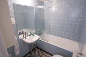 uma casa de banho em azulejos azuis com um lavatório e um chuveiro em Cosy Apartment in Frogner em Oslo