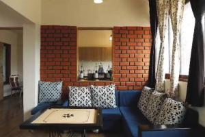 Sadashiv Bungalow - Kudje,3BHK with swimming pool في بيون: غرفة معيشة مع أريكة زرقاء وجدار من الطوب