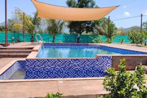 a swimming pool with blue tiles in a backyard at Sadashiv Bungalow - Kudje,3BHK with swimming pool in Pune