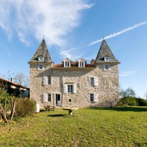 un gran edificio de piedra con dos torres en un campo en Château de Souhy, en Urcuit