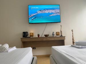 a room with two beds and a flat screen tv on the wall at Nicole Apartments Rental in Durrës