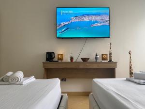 a room with two beds and a flat screen tv on the wall at Nicole Apartments Rental in Durrës
