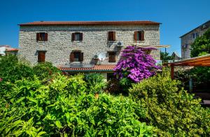 an old stone building with flowers in front of it at Vila Donna Apartments in Trogir