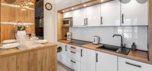 a kitchen with white cabinets and a sink at Holiday Family HANZA TOWER Pool & Sauna & Jacuzzi in Szczecin
