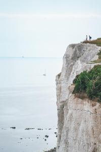 two people standing on a cliff near the ocean at The Lighthouse Cabin in Borre